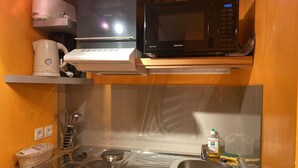 Een kleine keuken met een magnetron, koffiezetapparaat en een spoelbak.