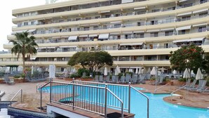 A multi-story hotel with a swimming pool, outdoor seating, and a palm tree. - 2 Bed Hotel Apt, Sleeps 4/6, Costa Adeje, 5 minutes walk to Beach, Shops & Bars (Costa Adeje)
