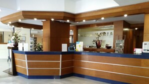 A reception desk with a wooden finish and blue accents, featuring a digital kiosk, informational brochures, and a vase with flowers. - 2 Bed Hotel Apt, Sleeps 4/6, Costa Adeje, 5 minutes walk to Beach, Shops & Bars (Costa Adeje)