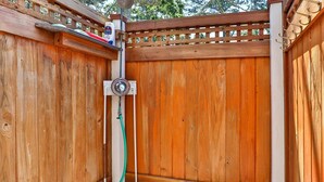 A wooden outdoor shower enclosure with a hose and a water bottle. - Family Oasis in Great Location with Pool (Harwich)