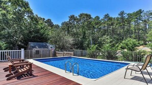 A swimming pool with a wooden deck, metal railings, and a basketball hoop. - Family Oasis in Great Location with Pool (Harwich)
