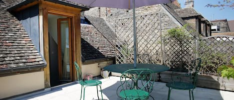 Une terrasse avec une table et des chaises, une porte et un mur en pierre.