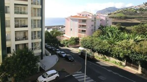 Ein mehrstöckiges Wohngebäude mit Balkonen, einem Parkplatz und Blick aufs Meer.