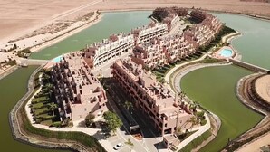Un ampio complesso alberghiero con diversi edifici, una strada centrale e una distesa d'acqua circostante.