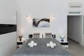 Une chambre d’hôtel moderne avec un grand lit, deux tables de chevet avec des lampes, un climatiseur fixé au mur et un tableau au-dessus du lit.