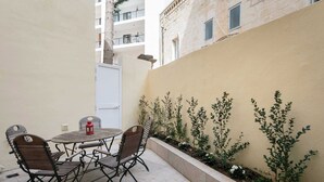 A patio with a table and chairs, a red lantern, and a low wall with plants. - 22 - Unique Four Bedroom Townhouse by PMI Malta (Tas-Sliema)