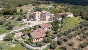 An aerial view of a countryside property with multiple buildings, stone walls, and a well-maintained garden.