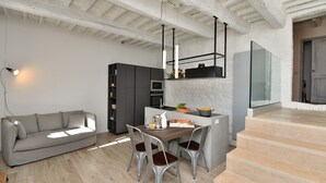 Eine moderne Küche mit Essbereich, einem grauen Sofa und einer Treppe, die zu einer weiteren Ebene führt.