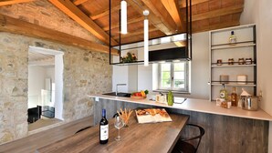 Cozinha moderna com parede de pedra, vigas de madeira, adega embutida e uma janela ampla.