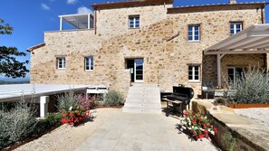 Un bâtiment en pierre doté d’un patio, d’un espace extérieur aménagé avec des sièges et d’un barbecue.