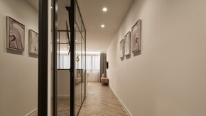 A modern hallway with wooden flooring, glass partitions, and artwork on the walls. - Hestia - Dimitressa 4 (Athens)