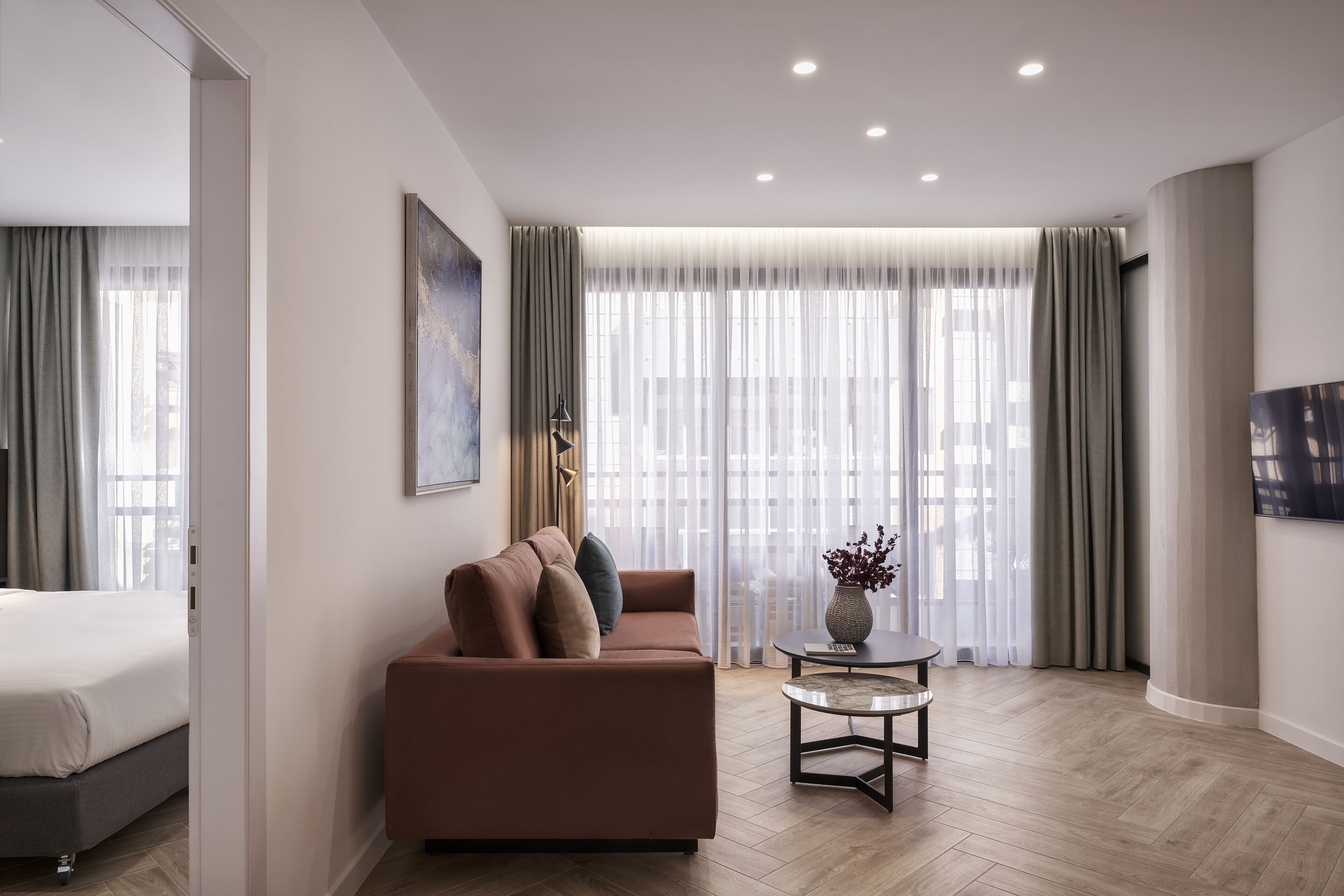 A modern hotel room with a sofa, a small table, and a bed.