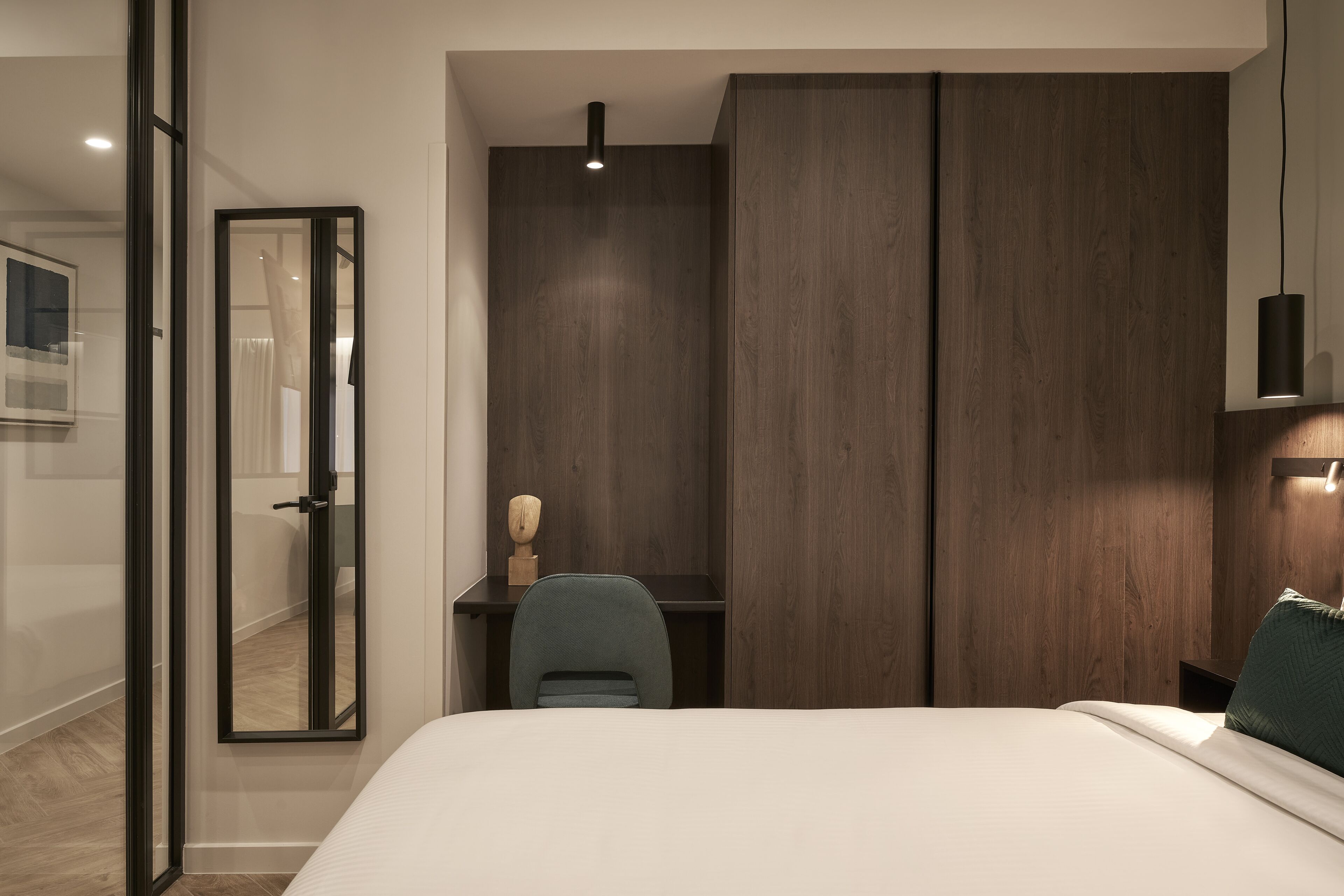Ein modernes Schlafzimmer mit einem großen Bett, einem Schreibtisch und einem Kleiderschrank.