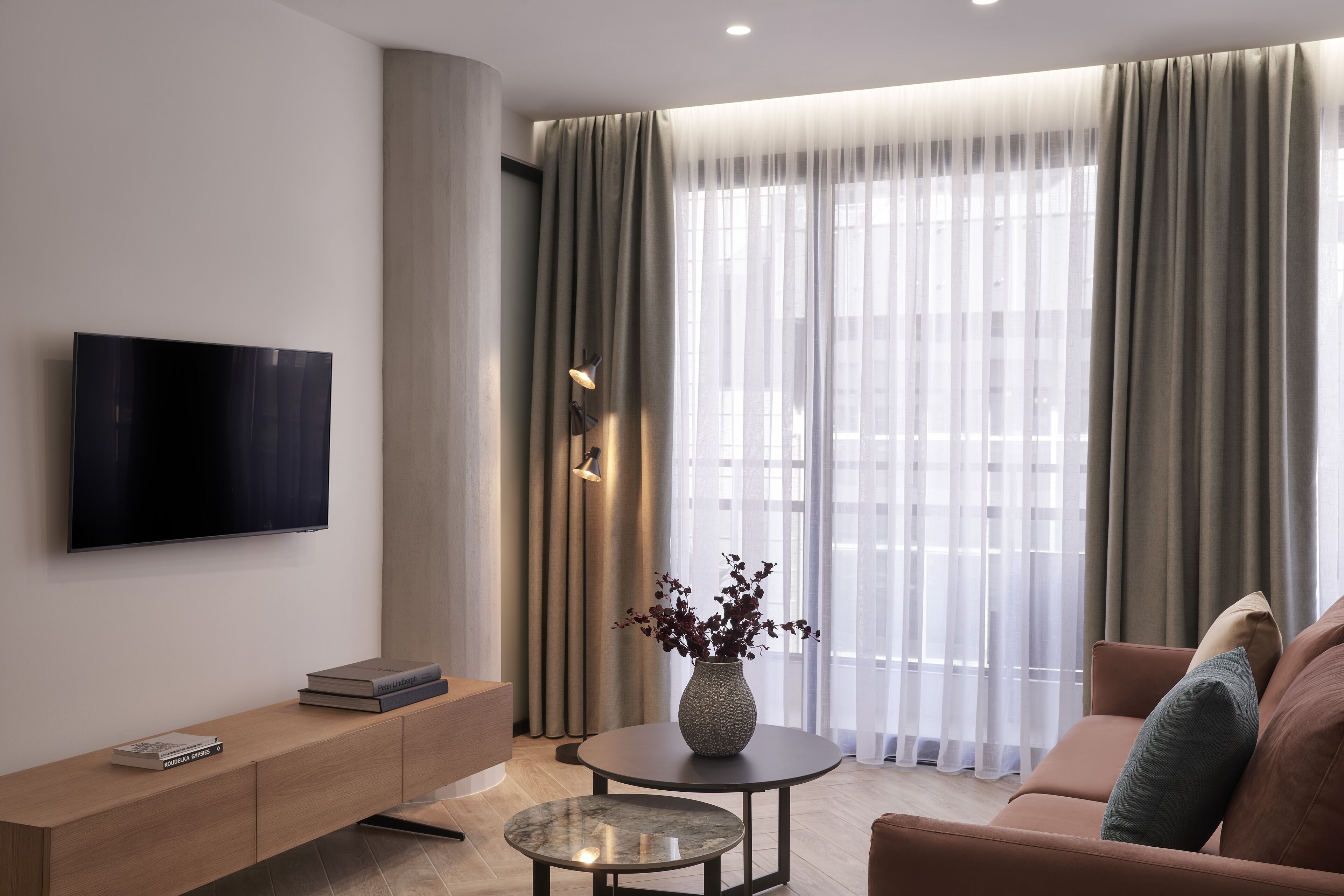 A modern living room with a flat-screen TV, a wooden console table, a round coffee table, and a sofa.