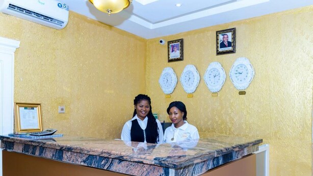 Un comptoir d’accueil avec un plateau en marbre, des certificats encadrés accrochés au mur et une horloge.
