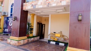 L’entrée d’un hôtel, avec une façade recouverte de carreaux, un vélo garé à l’extérieur et une banderole faisant la publicité de la collection Prince & Bryan.