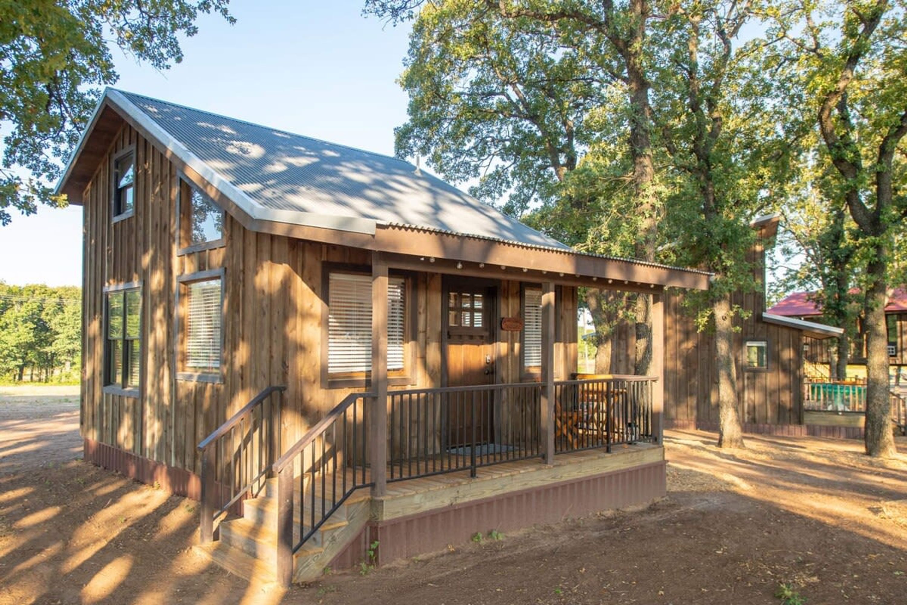 A rustic wooden cabin with a porch, large windows, and a metal roof.