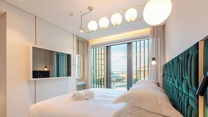 A modern hotel room with a large bed, a built-in TV, and a view of the city through the window. - Luster Hotel (Lisbon)