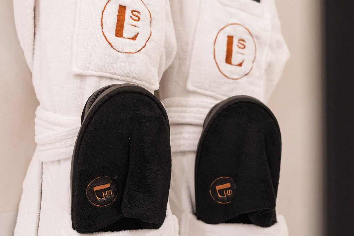 A pair of white bathrobes with a logo and a tag.