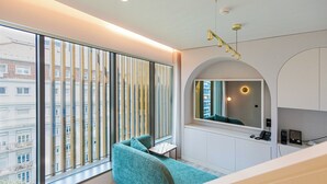 Een moderne slaapkamer met een groot raam, een bank, een kleine tafel en een spiegel.
