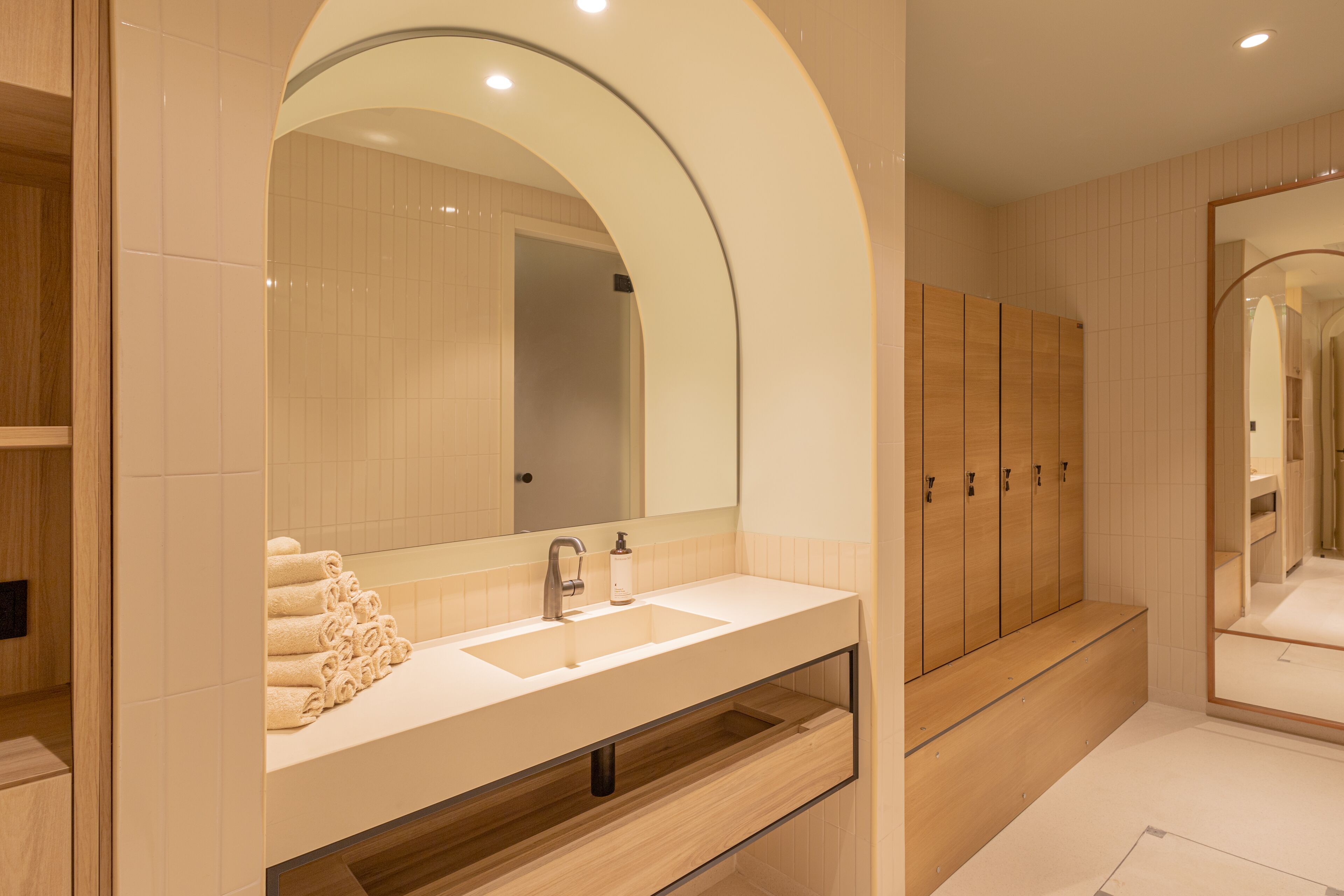 A modern bathroom with a large sink, mirror, and wooden cabinets.