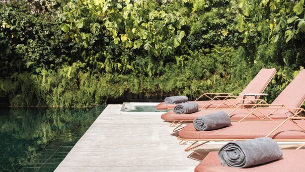 A poolside area with lounge chairs and a green-tiled pool. - Luster Hotel (Lisbon)