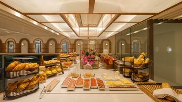 A breakfast buffet with various food items and a floral centerpiece.