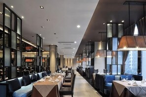 A modern restaurant with long tables and booths, high ceilings, and large windows. - Xindao International Hotel (Yichang)