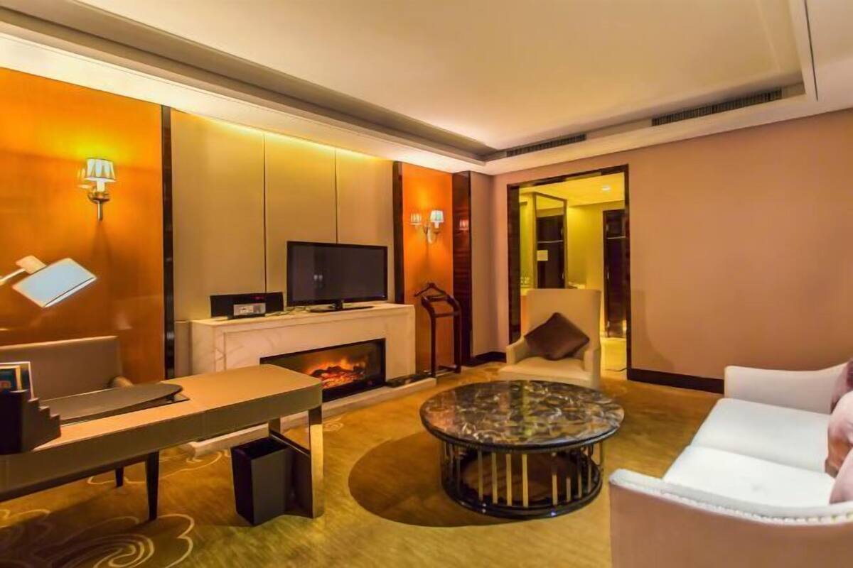 A modern living room with a fireplace, a television, a sofa, a coffee table, and a desk with a computer.