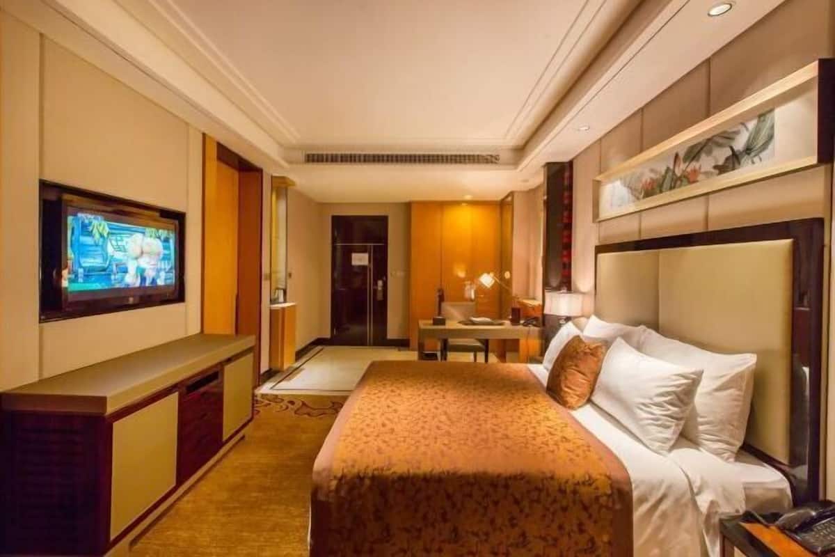 A hotel room with a bed, a television, a desk, and a chair.