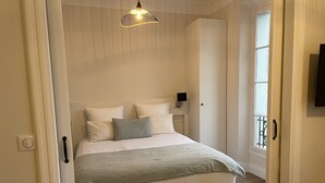 Una camera da letto con un letto, un comodino, una TV a parete e una finestra con balcone.