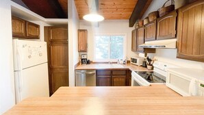 Una cucina con mobili in legno, un frigorifero, un fornello e un forno a microonde.