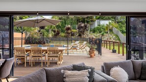 Une vaste terrasse extérieure dotée d’une piscine, de chaises longues et d’un espace repas.
