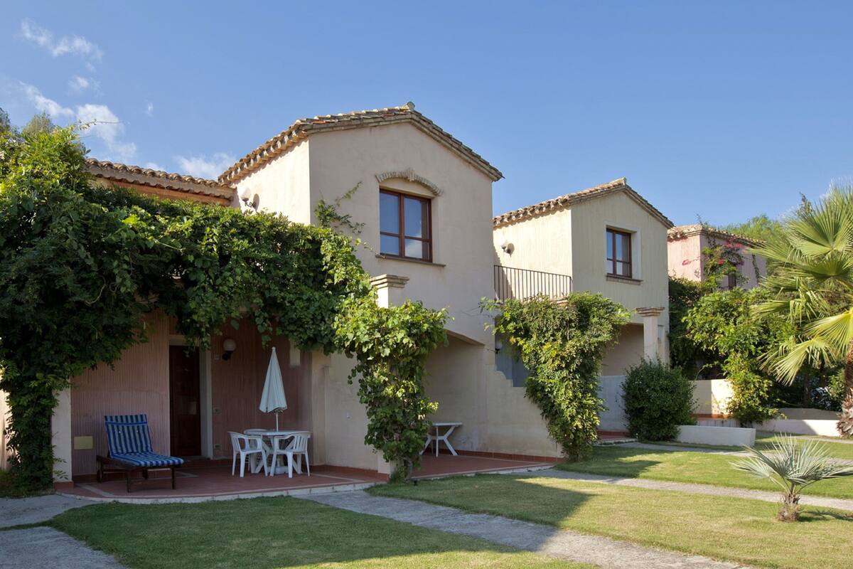 A two-story house with a patio area, a small table, and chairs.