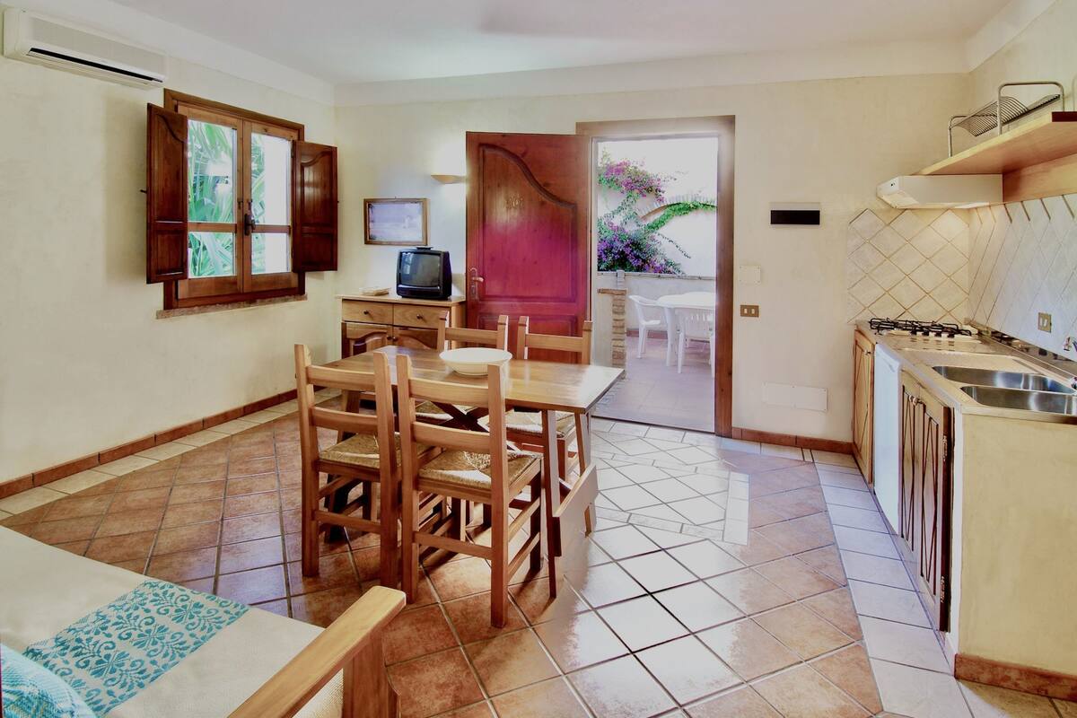 A compact kitchen with a dining area, a TV, and a view of the outdoors.