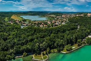 Vista aérea de un pueblo a orillas de un lago, con abundante vegetación, aguas cristalinas y una combinación de edificios residenciales y comerciales.