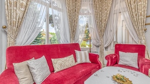 A room with a red sofa and armchairs, a round table with a white tablecloth, and sheer curtains with gold patterns. - Treasure Of The Past With Whirlpool (Balatonrendes)