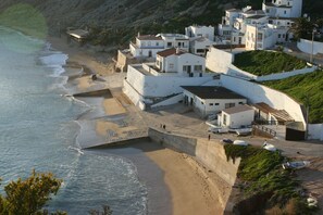 A coastal village with white buildings, a beach, and a rocky hillside. - Casa Valeria right by sea, ground floor, 2 bedrooms, roof terrace, beach, view (Budens)