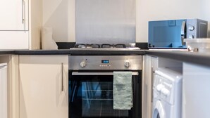 Une cuisine moderne dotée d’une hotte en acier inoxydable, d’un four encastré et d’un lave-linge à chargement frontal.