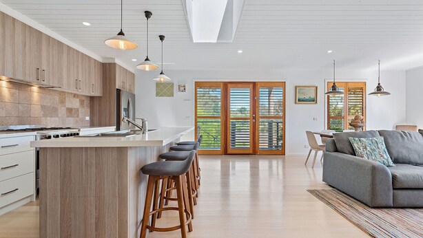 Una cocina moderna con una isla central, taburetes de bar e iluminación colgante.