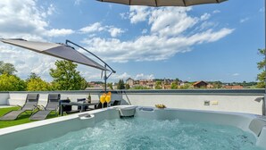 Un jacuzzi con vistas a un pueblo, sillones de descanso y una pérgola.