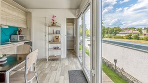 Una cocina moderna con comedor, una escalera que sube a un nivel superior y vistas a una zona residencial a través de amplios ventanales.