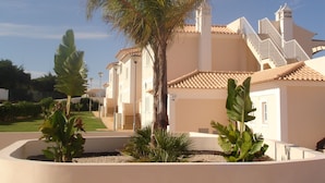 A building with a tiled roof, a staircase, and a palm tree in the foreground. - Magnificent 2 bedroom ground floor apartment, wi-fi, pool, garden, near beach and golf - Galé, Albufeira (Albufeira)