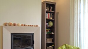 A living room with a fireplace, a tall bookshelf, and a green bean bag chair. - Magnificent 2 bedroom ground floor apartment, wi-fi, pool, garden, near beach and golf - Galé, Albufeira (Albufeira)