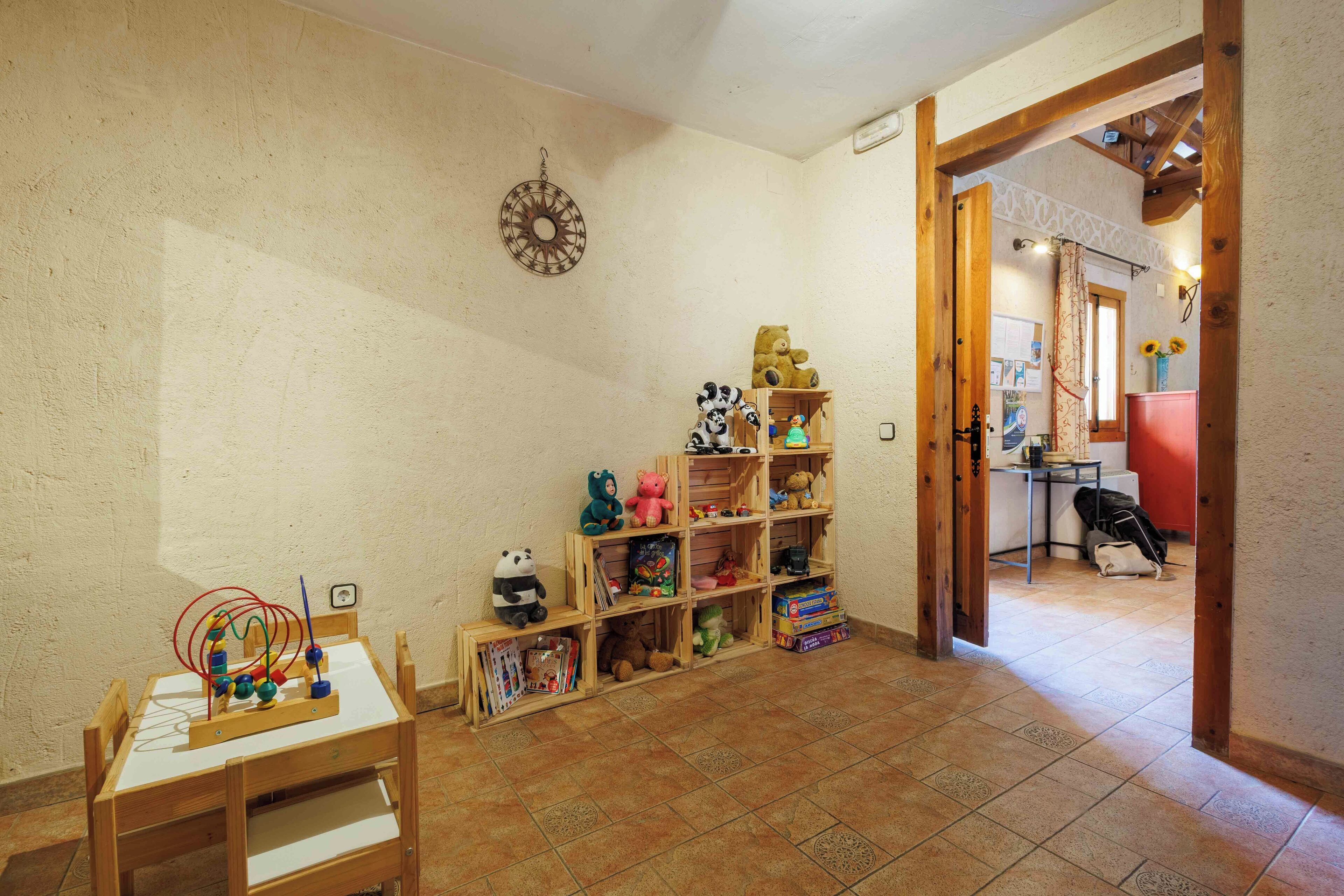 A room with a wooden play area, a bookshelf, and a door leading to another room.
