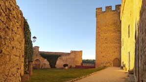 A medieval castle courtyard with stone walls, a gravel path, and a grassy area. - La Cerca Entre Hoces - 10-20pax-Large common spaces (Sebúlcor)
