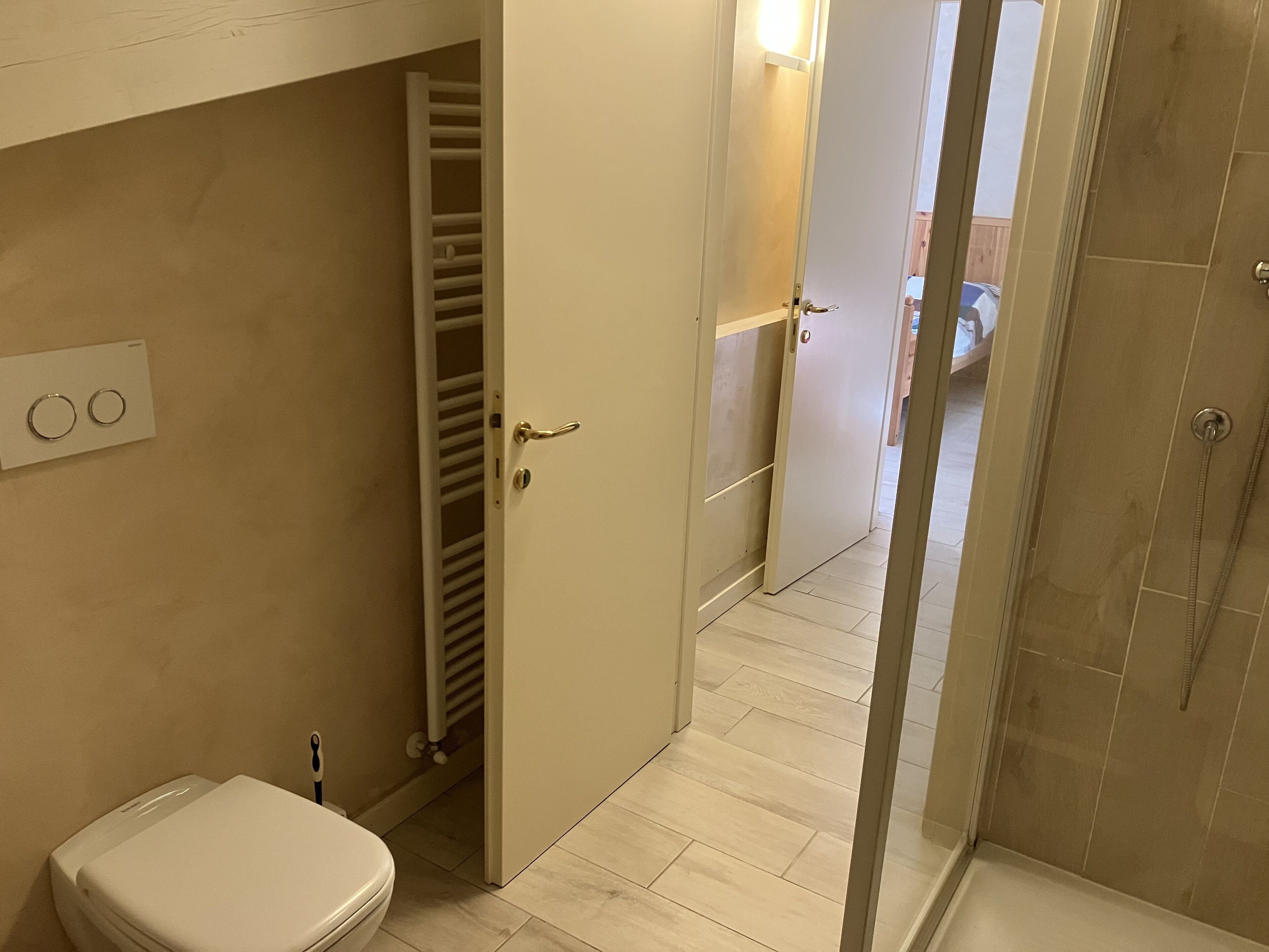 Ein Badezimmer mit Toilette, einer begehbaren Dusche und einer Tür zu einem Flur.