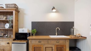 Une cuisine avec des meubles de rangement en bois, un four à micro-ondes, un évier et un petit réfrigérateur.