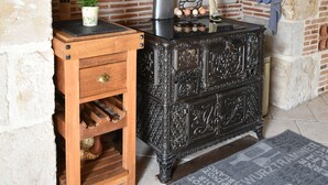 Una cocina rústica con pared de ladrillo, una mesa de madera con una planta en maceta y una estufa antigua.