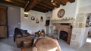 Una sala rústica con sofás de cuero, chimenea de piedra y techo de madera.